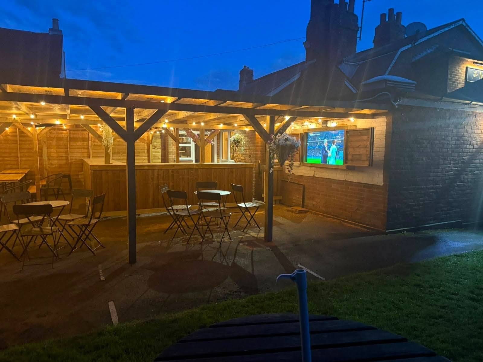 The large outdoor screen showing football in the covered garden at The Maypole Inn
