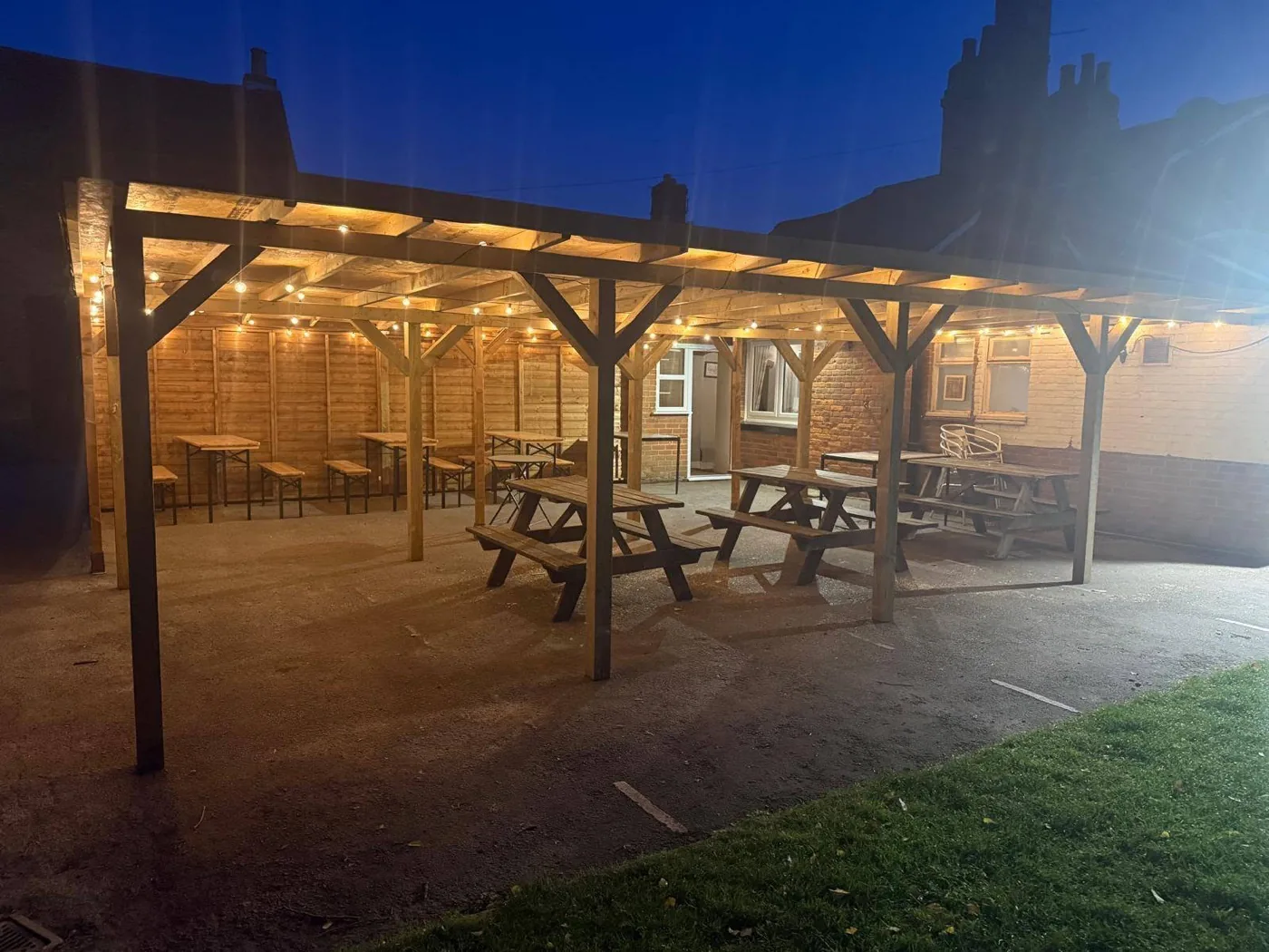 The covered beer garden lit by festoon lights at dusk